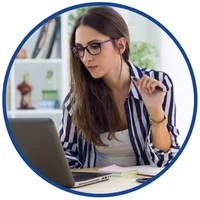 Kurs kadry i płace dla średniozaawansowanych – kobieta z długopisem w dłoni patrzy w ekran laptopa