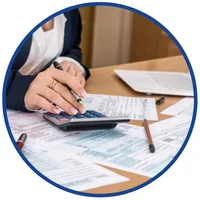 Kursy online z rachunkowości i finansów, m.in. Akcja Bilans – dłonie z długopisem nad kalkulatorem i formularzami