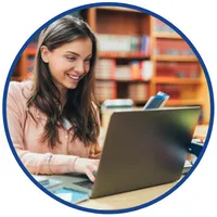 Kurs online z prawa zamówień publicznych – kobieta pracuje na laptopie w bibliotece, trzymając telefon